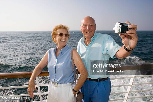 mature couple taking picture on cruise ship, smiling - senior colored hair stock pictures, royalty-free photos & images