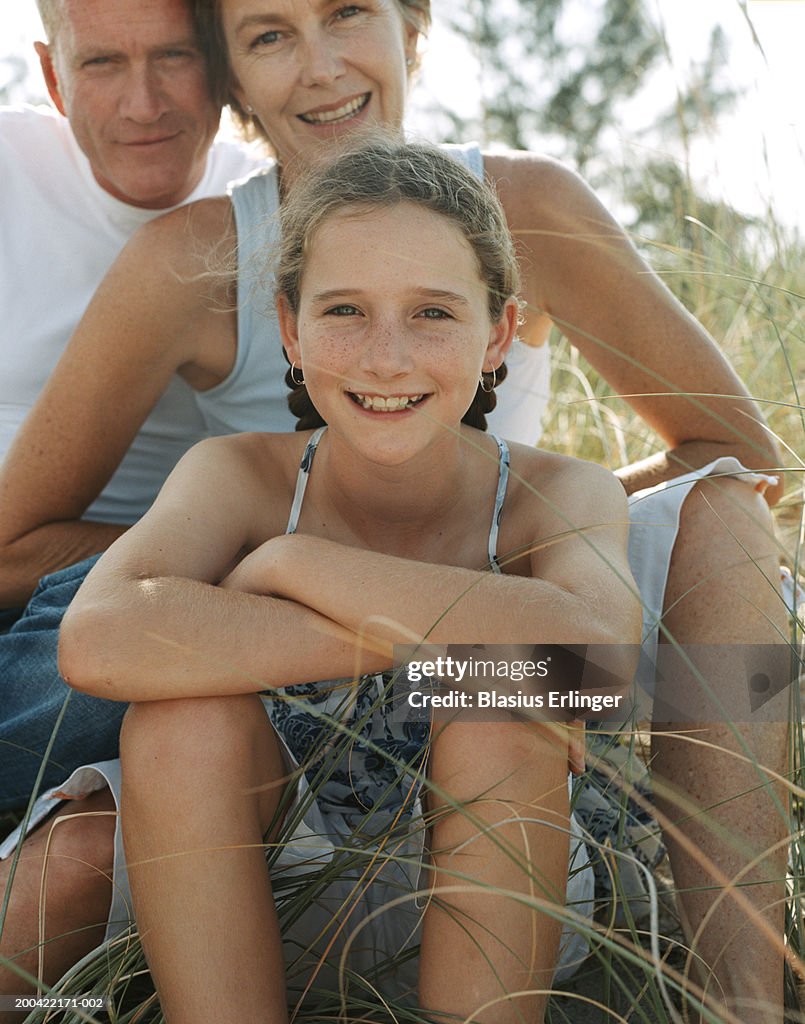 Family sitting on rocks at beach, smiling, portrait, close-up