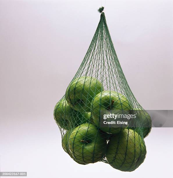 granny smith apples hanging in a net - netting 個照片及圖片檔