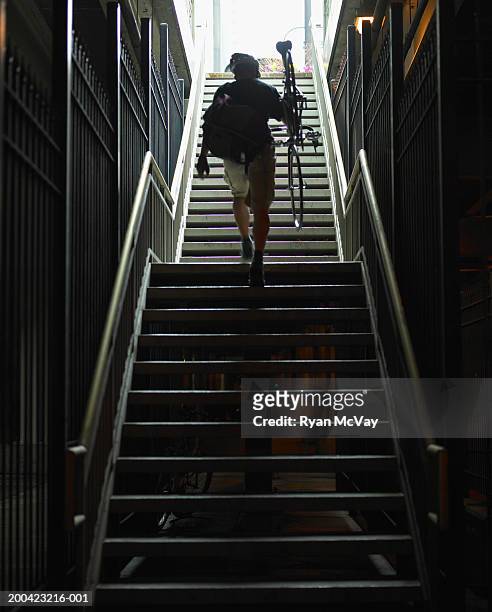 man with bicycle walking up subway stairs, rear view - metrostation stockfoto's en -beelden