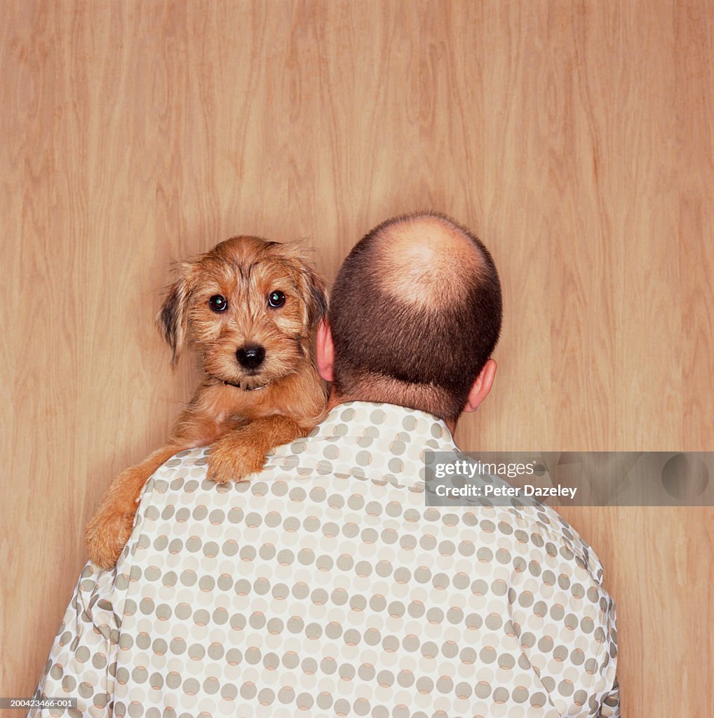 Man with puppy on shoulder, rear view