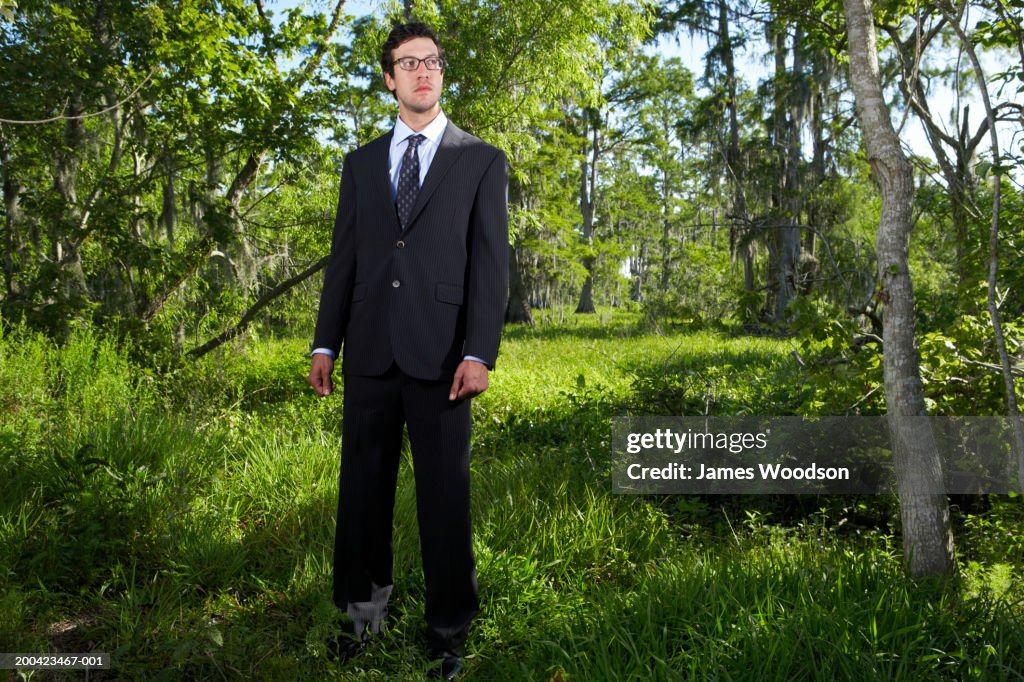 Businessman standing in woods