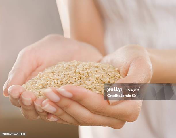 woman holding handful of brown rice, close-up - rice grain foto e immagini stock