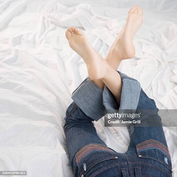 woman lying on bed, low section, rear view, elevated view - woman lying on stomach with feet up stock pictures, royalty-free photos & images