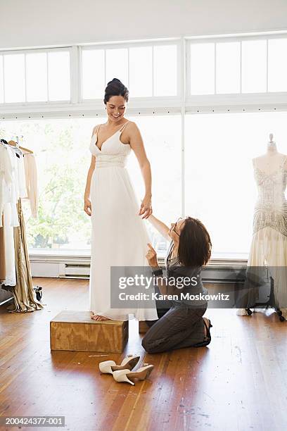 woman adjusting bride's wedding dress during fitting - bridal shop stock pictures, royalty-free photos & images