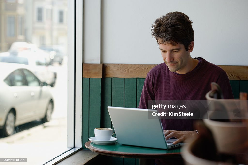 Man sitting in cafe, working on laptop