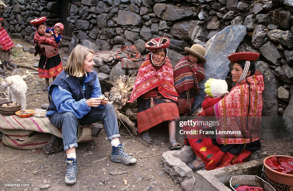 Peru, Huilco, female tourist sitting with woman holding baby, smiling