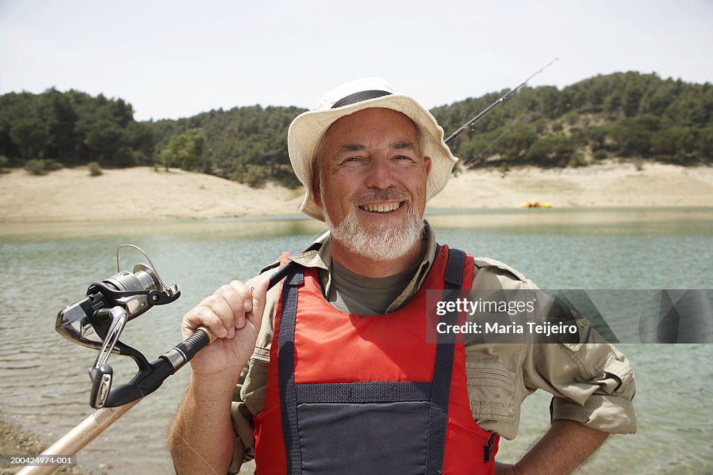 Mature Man Holding Fishing Rod Over Shoulder Smiling Portrait High-Res  Stock Photo - Getty Images