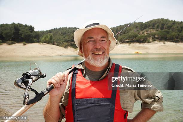 mature man holding fishing rod over shoulder, smiling, portrait - rod stock pictures, royalty-free photos & images