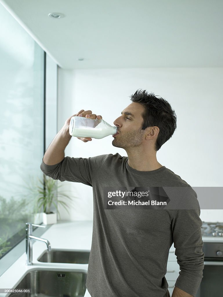 Man drinking bottle of milk in kitchen