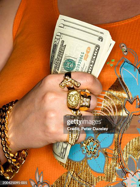 woman wearing gold jewellery, holding us dollar banknotes, mid section - begehren stock-fotos und bilder