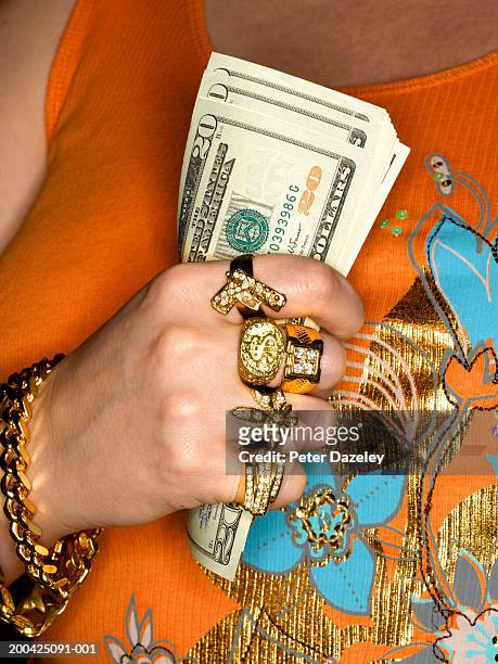 woman wearing gold jewellery, holding us dollar banknotes, mid section - bling bling fotografías e imágenes de stock