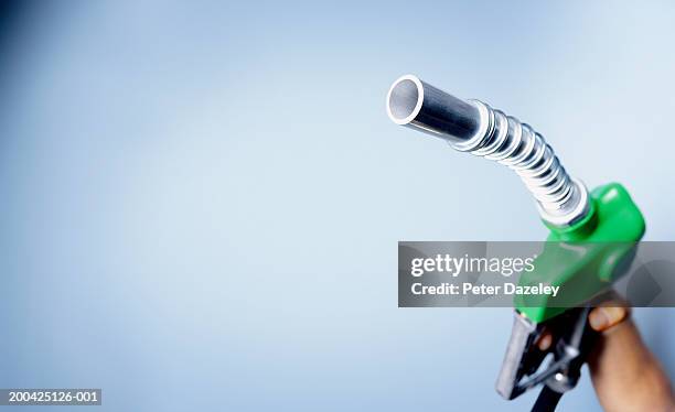 man holding up petrol pump nozzle, close-up - refuelling stock-fotos und bilder