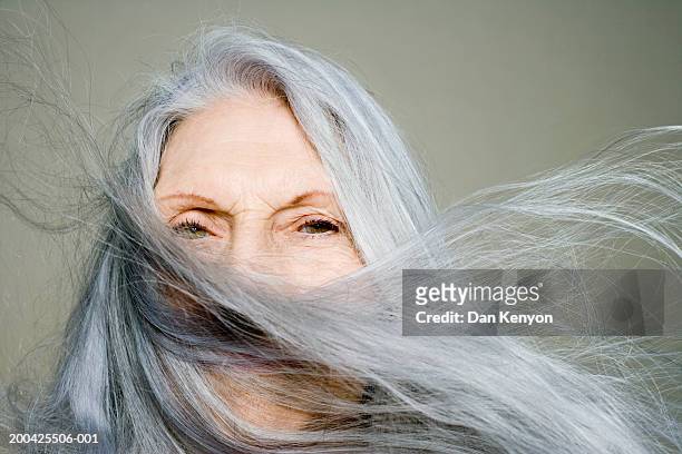 senior woman with long hair blowing across face, portrait, close-up - capelli grigi foto e immagini stock