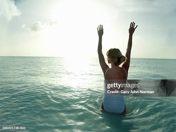 woman lifting arms in ocean, rear view - darkwood beach foto e immagini stock