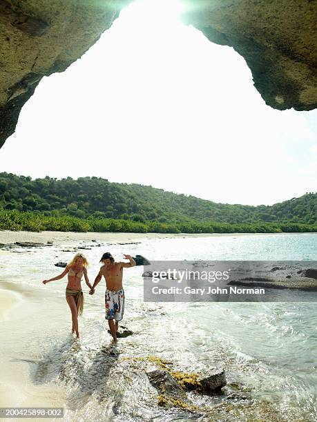 couple walking through surf on beach, smiling - caribbean sea foto e immagini stock