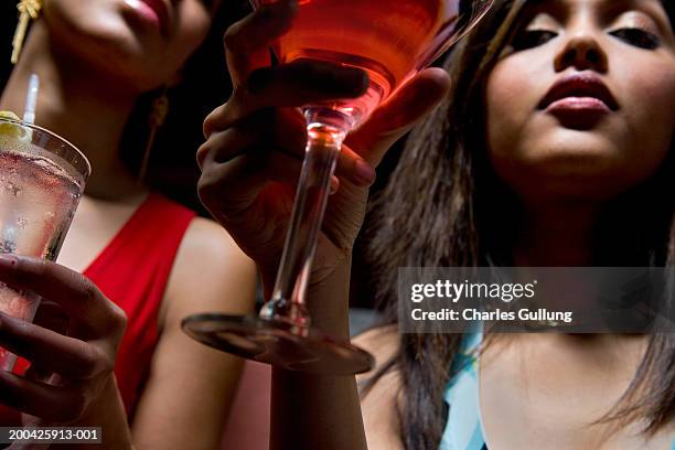two young women holding cocktails, low angle view - low alcohol drink stock pictures, royalty-free photos & images