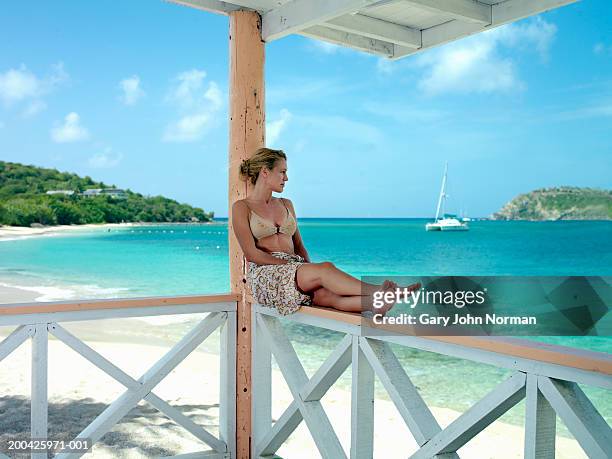 woman sitting on verandah railing, looking at ocean - antigua and barbuda stock pictures, royalty-free photos & images