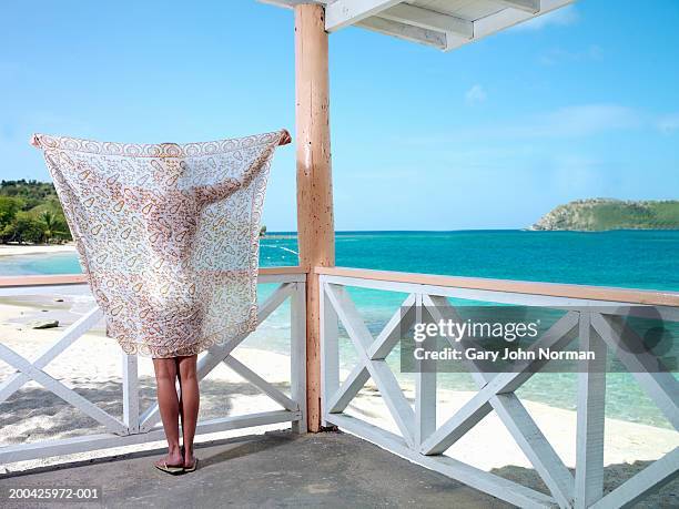 woman holding up sarong on verandah, rear view - sarong stock pictures, royalty-free photos & images