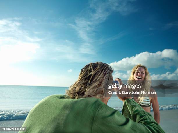 man taking picture of woman on beach, smiling, close-up - darkwood beach foto e immagini stock