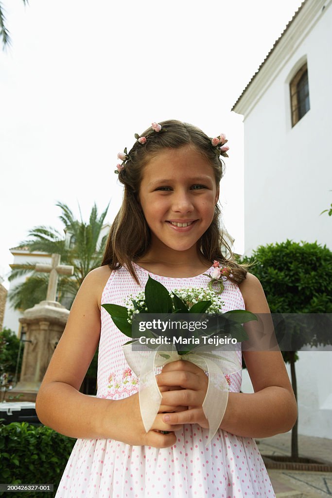 Flower girl (7-9) holding bouquet, smiling, portrait