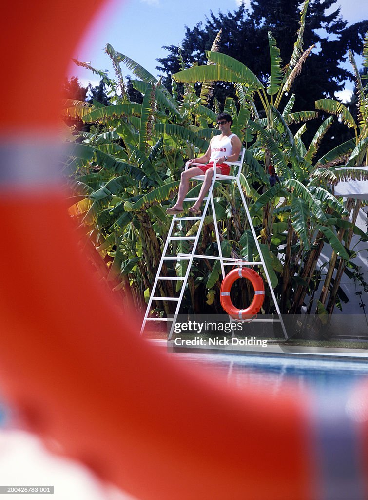 Lifeguard sitting on tower at pool, outdoors