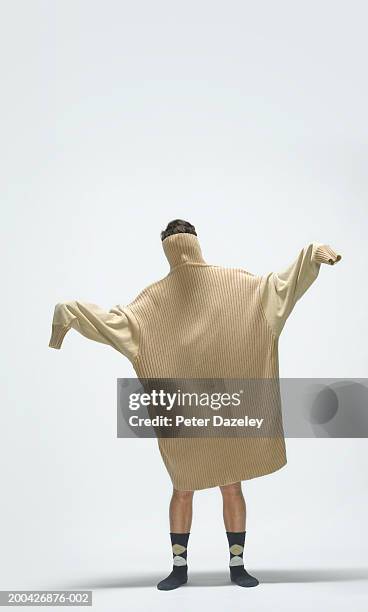 young man wearing large jumper over head and body, arms outstretched - sleeve stock-fotos und bilder