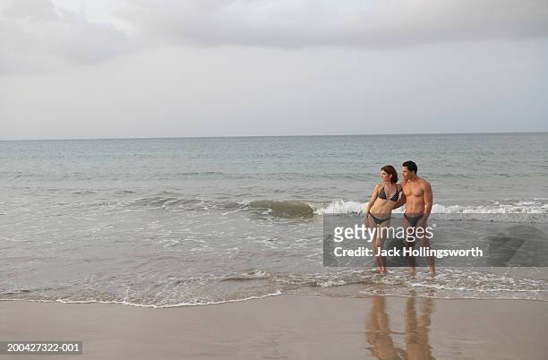 young couple wearing swimwear and standing on the beach - young men in speedos 個照片及圖片檔