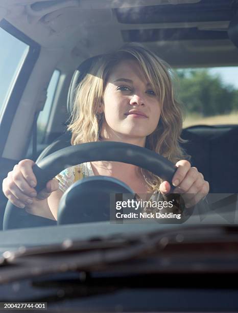 young woman driving car, smiling, close-up, view through windscreen - driving car front view stock pictures, royalty-free photos & images