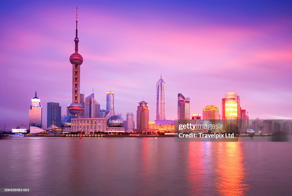 China, Shanghai city skyline, view across Huangpu River, sunset