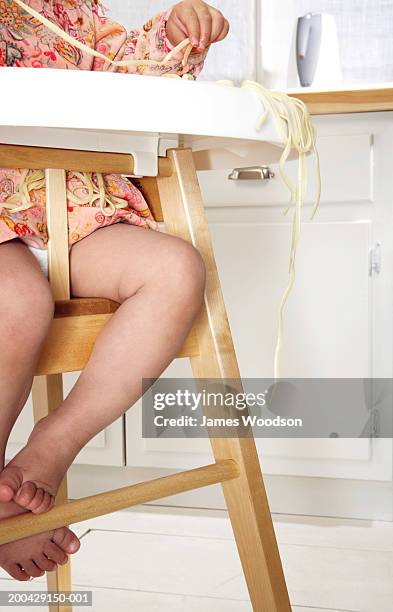 baby girl (18-24 months) in high chair, spaghetti hanging over tray - one baby girl only fotografías e imágenes de stock
