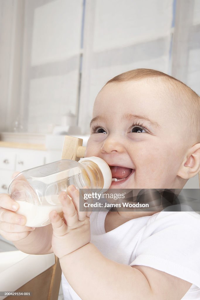 Baby girl (5-7 months) drinking milk from bottle, smiling