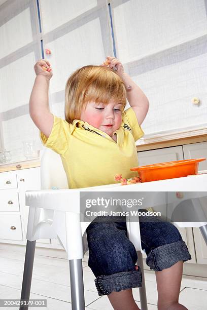 baby boy (14-16 months) in high chair throwing cereal - throwing food stock pictures, royalty-free photos & images