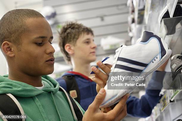 teenage boys (16-18) looking at training shoes in shop - sportswear shopping stockfoto's en -beelden