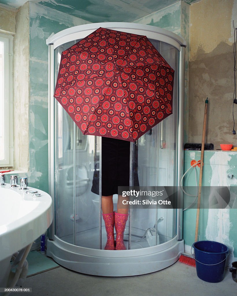 Woman standing under umbrella in shower stall