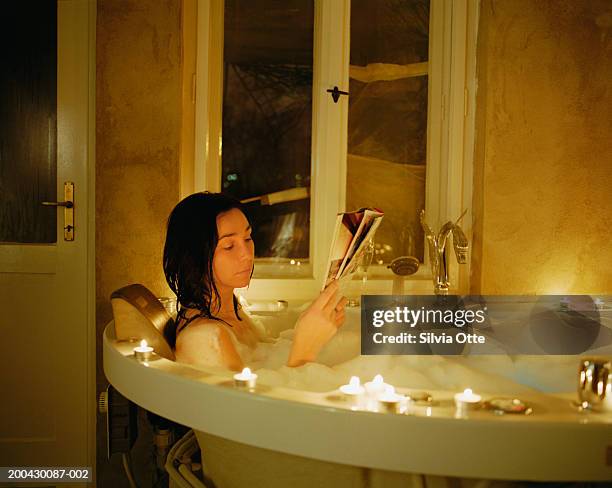 woman reading in bath - woman bath tub wet hair stock pictures, royalty-free photos & images