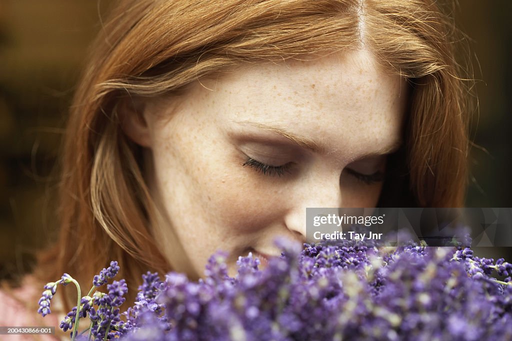 Young woman smelling lavendar, eyes closed, close-up