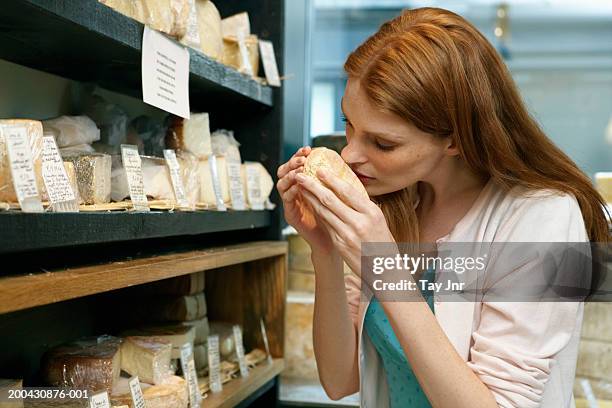 young woman in shop smelling cheese, close-up - smelling food stock pictures, royalty-free photos & images