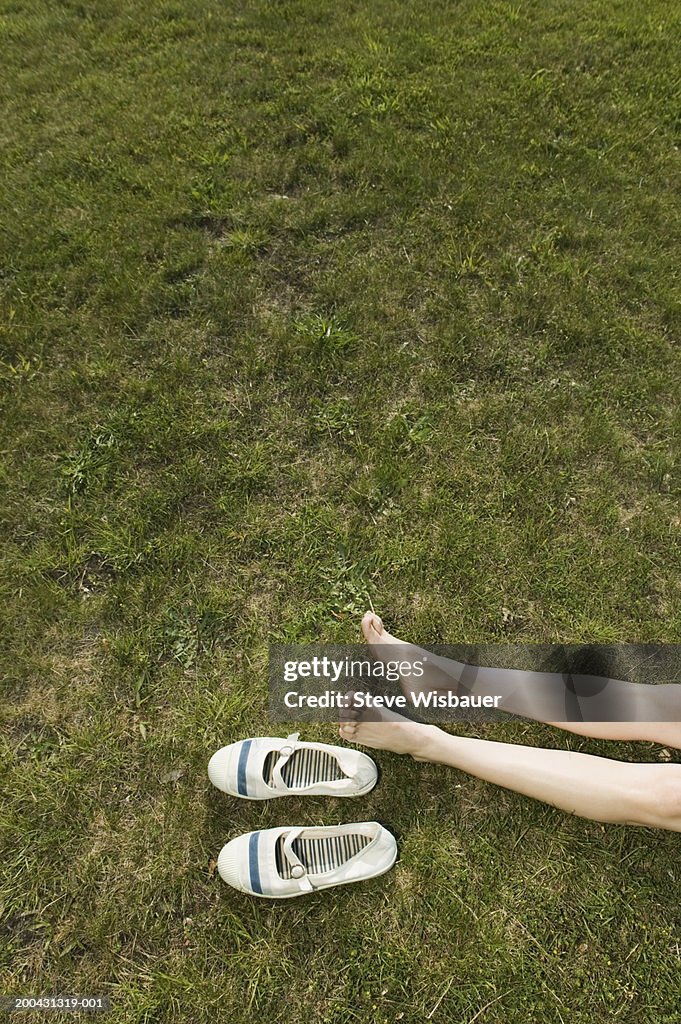 Woman lying on lawn, low section, elevated view