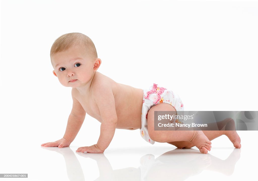 Baby girl (6-9 months) crawling on floor, portrait