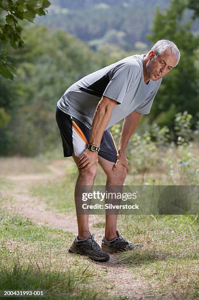 mature man on dirt track, hands on knees, catching breath - fatigue full body stock pictures, royalty-free photos & images