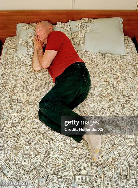 senior man sleeping on bed covered with us banknotes, elevated view - greed fotografías e imágenes de stock