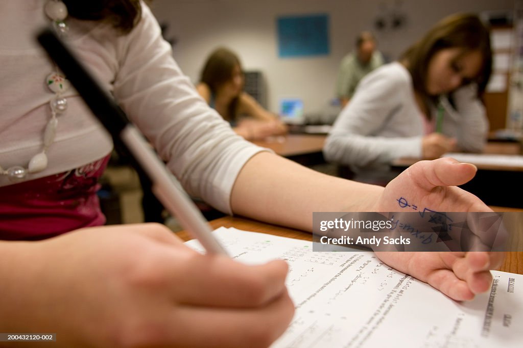 Teenage girl (15-17) cheating on math test (focus on formula on hand)