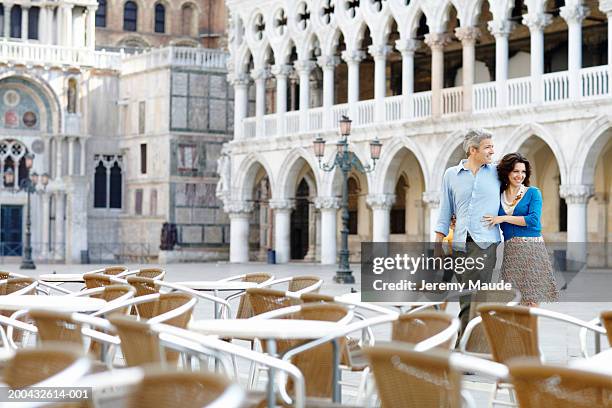 italy, venice, couple walking towards cafe with outdoor seating - italy city break stock pictures, royalty-free photos & images