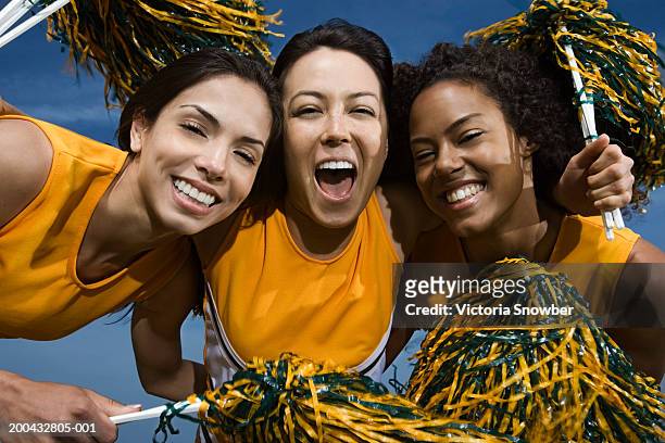 three female cheerleaders holding pompoms, smiling - asian cheerleaders ストックフォトと画像