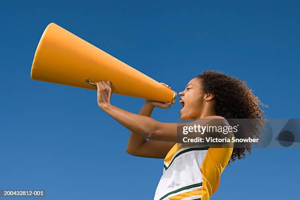 female cheerleader shouting into megaphone - cheerleaders stock pictures, royalty-free photos & images