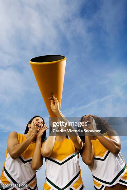 female cheerleaders shouting through megaphone, low angle view - asian cheerleaders stock-fotos und bilder