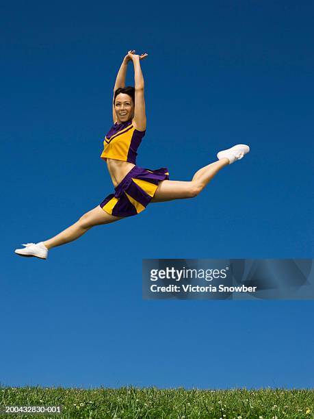 female cheerleader leaping in air - asian cheerleaders stock-fotos und bilder