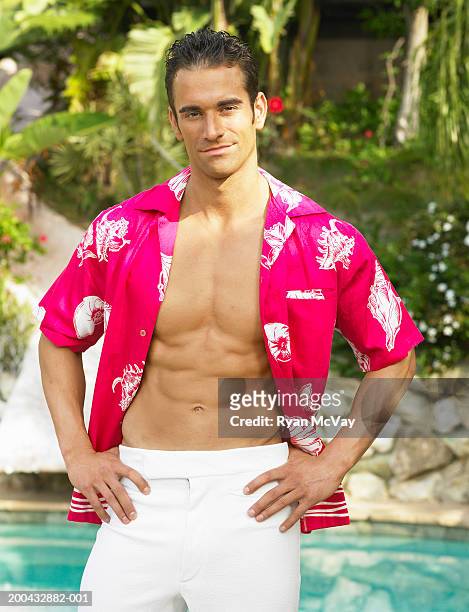 young man standing beside swimming pool, hands on hips, portrait - desabrochado fotografías e imágenes de stock