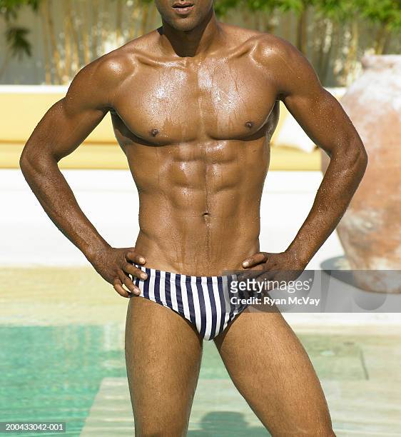 man in racing briefs standing beside pool, hands on hips, mid section - man wearing speedo stock-fotos und bilder